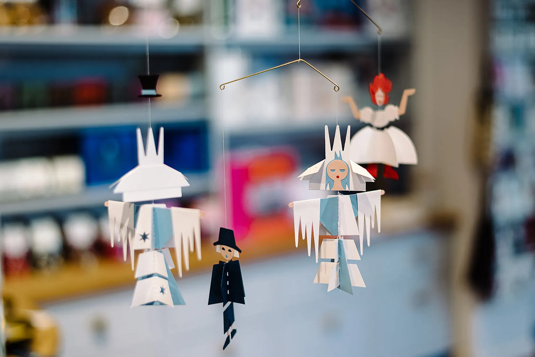 Handmade paper mobile with fairy tale-inspired characters suspended from a delicate wire frame, displayed indoors.