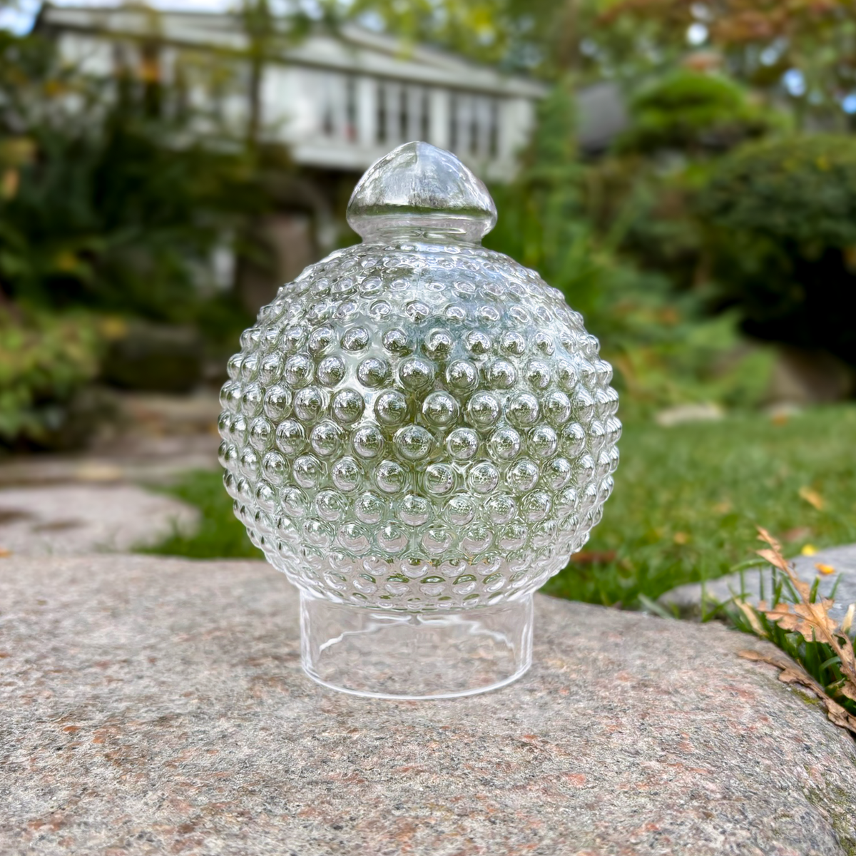 Gennemsigtig Holmegaard glas lyskuppel på en sten med naturbaggrund