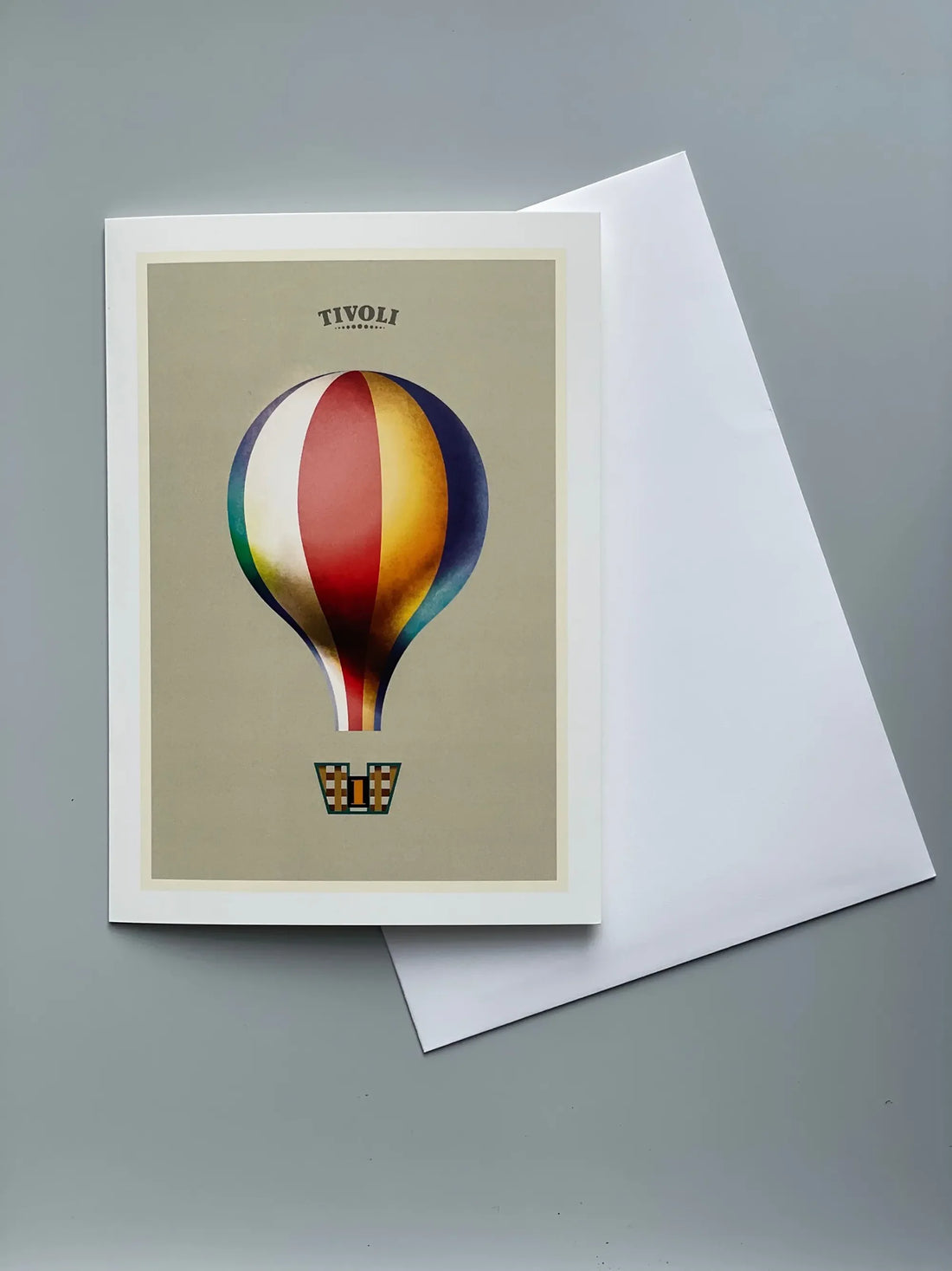 Foldekort med Mads Berg illustration af Tivolis ikoniske Ballongynge, fotograferet foran forlystelsen med farverige luftballoner i baggrunden.