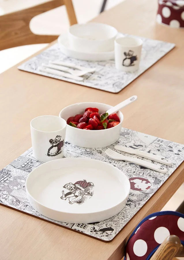 Dinner setting with white dishes featuring Rasmus Klump characters on a wooden table.