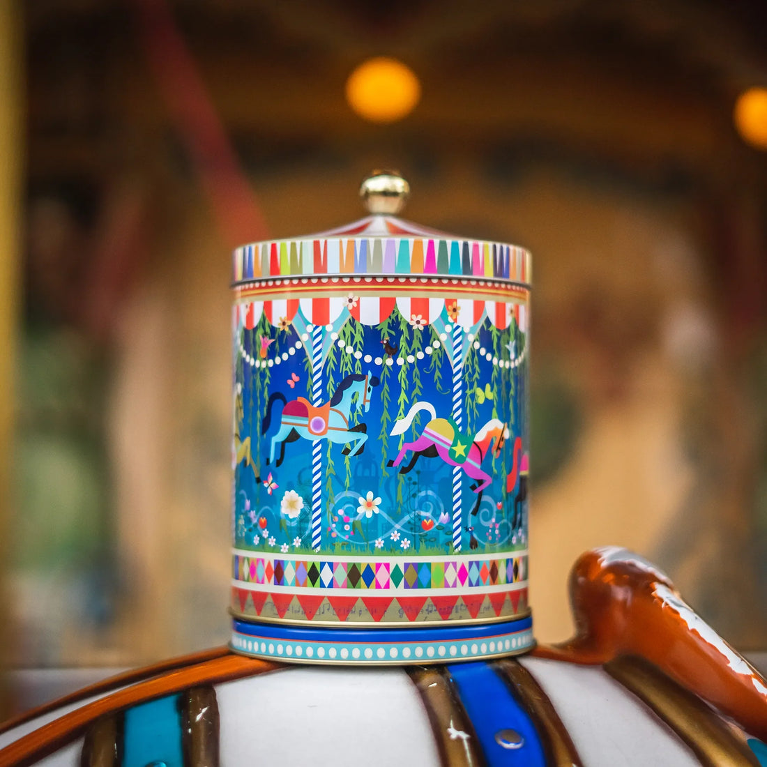 Farverig Tivoli karrusel kagedåse i metal med dekorativt motiv af karusselheste og Tivoli-inspireret design
