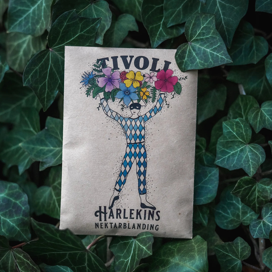 Harlekins Nektarblanding fra Tivoli, bivenlig blomsterblanding med nektarrige blomster, der tiltrækker bier, sommerfugle og andre bestøvere, illustreret med Tivolis ikoniske Harlekinfigur
