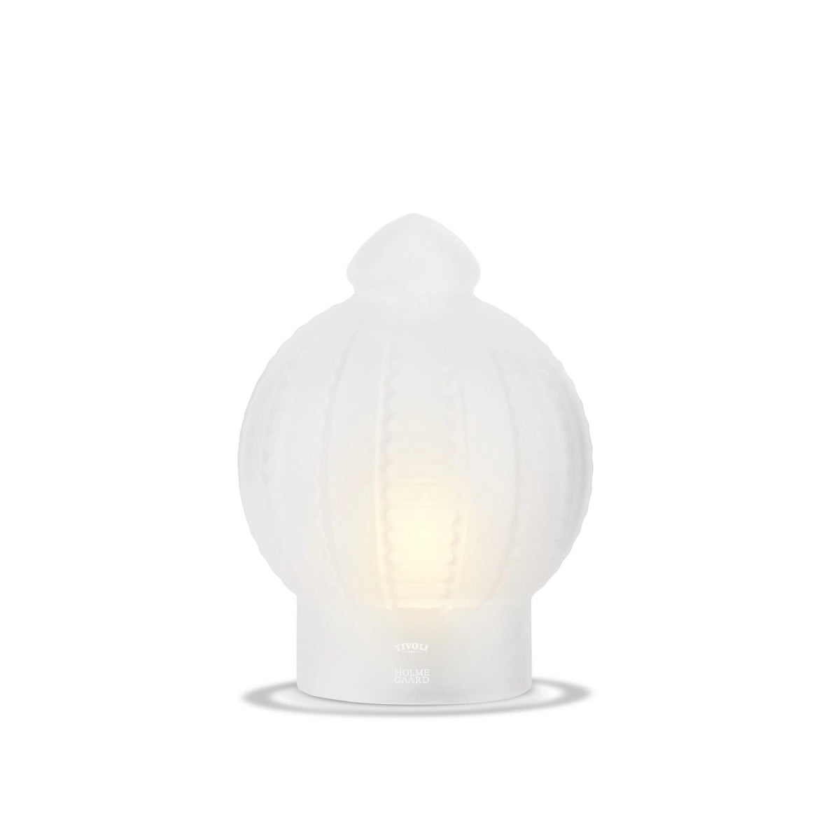 Tivoli x Holmegaard glaslampe i hvidt opalglas med dekorative lodrette relieffer og blødt lys, der stråler gennem glasset. Lampen har en karakteristisk kuppelformet top og fod med diskret Tivoli x Holmegaard-logo.