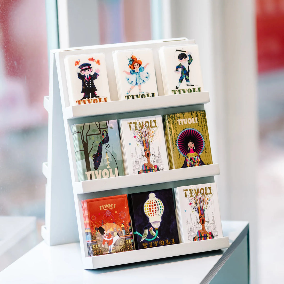 Tivoli magnet med det klassiske Ib Antoni-design, der viser den ikoniske Tivoli-lampe og et fuglepar, inspireret af Tivolis stemningsfulde belysning og danske designtradition