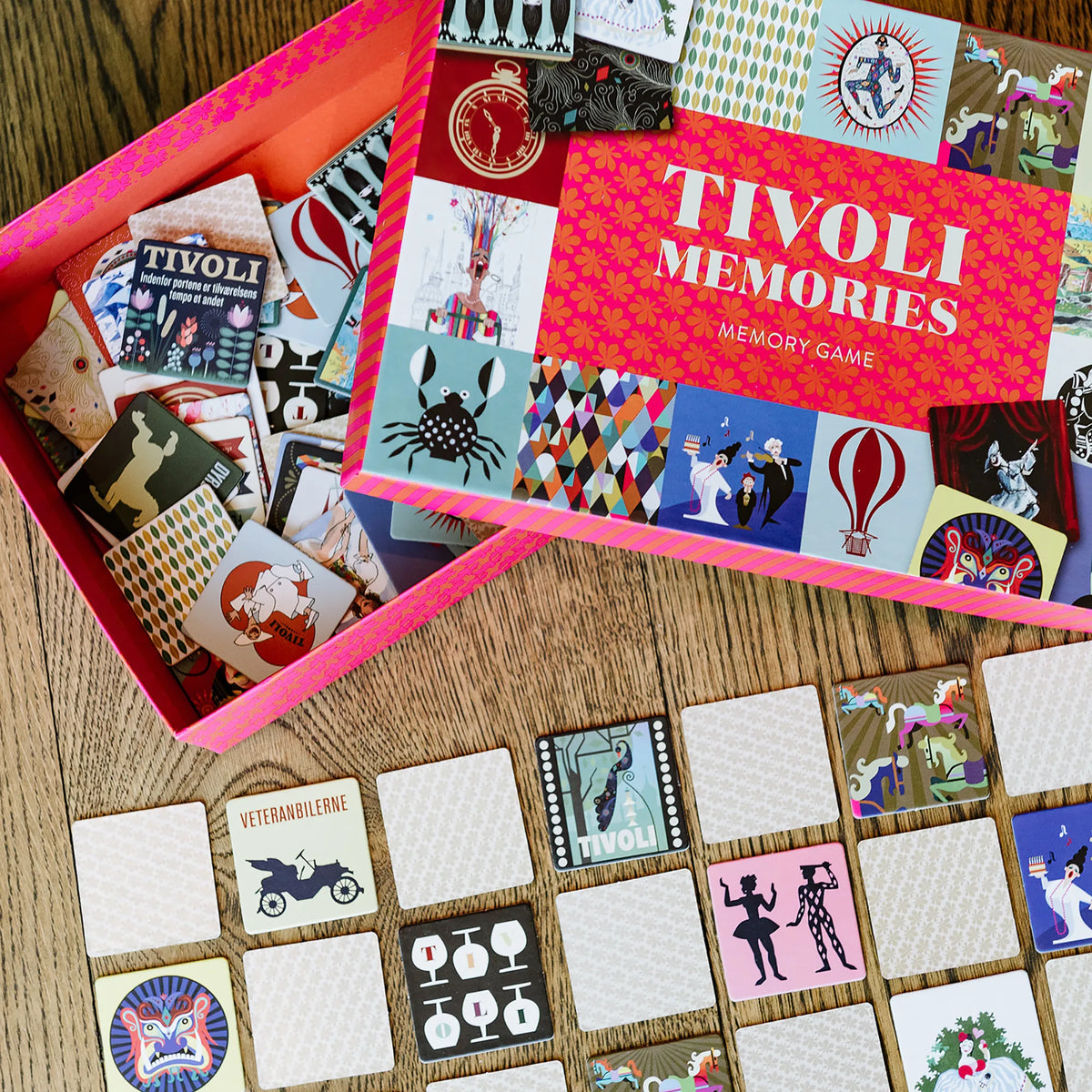 Tivoli Memories memory game med åben spilæske og farverige brikker med historiske Tivoli-motiver, et familievenligt vendespil der træner hukommelse og koncentration