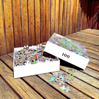 Colourful 100-piece Tivoli Gardens puzzle by IC4, featuring detailed illustrations of Copenhagen’s iconic amusement park, puzzle box and loose pieces on a wooden surface.