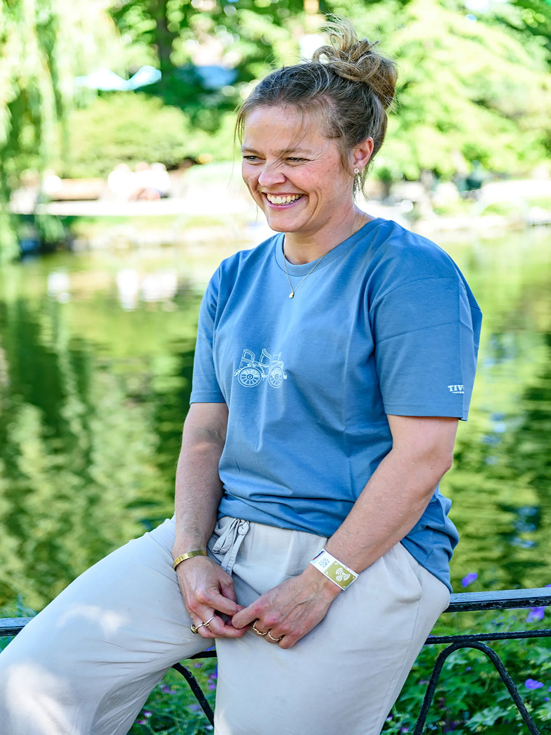 Blå Tivoli T-shirt i blød kvalitet med diskret brystprint, vist i naturskønne omgivelser ved Tivoli Søen i København.